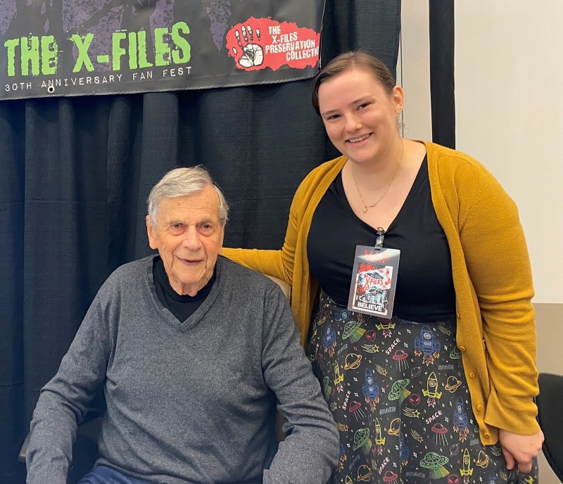 Courtney standing next to William B. Davis, who is seated.